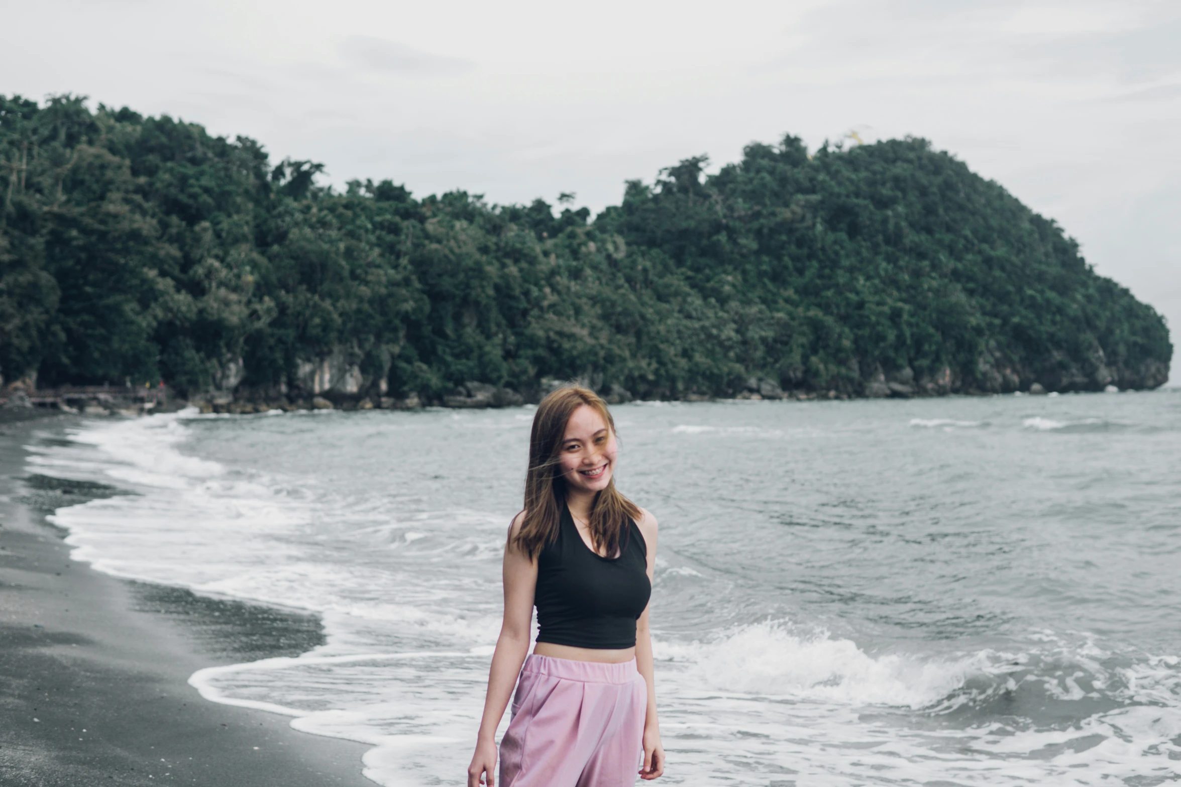 a woman standing on top of a sandy beach next to the ocean