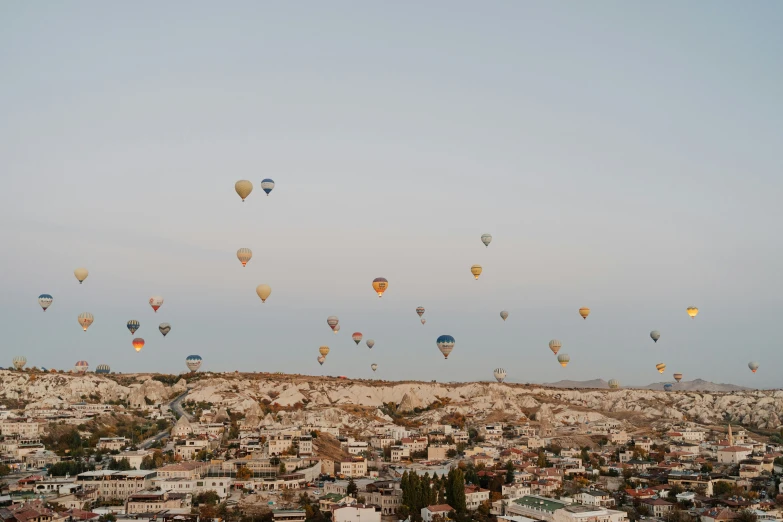 many balloons flying above a city on a sunny day