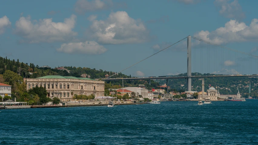 a boat traveling past a large bridge over water