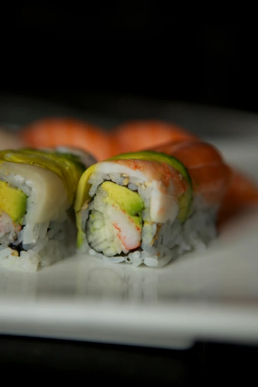 two sushi rolls sit on a white plate