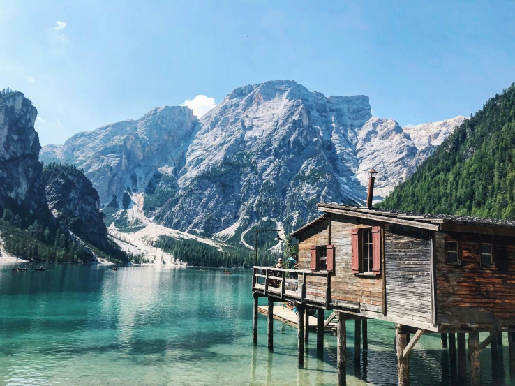 the boat house sits on a dock next to a mountain lake