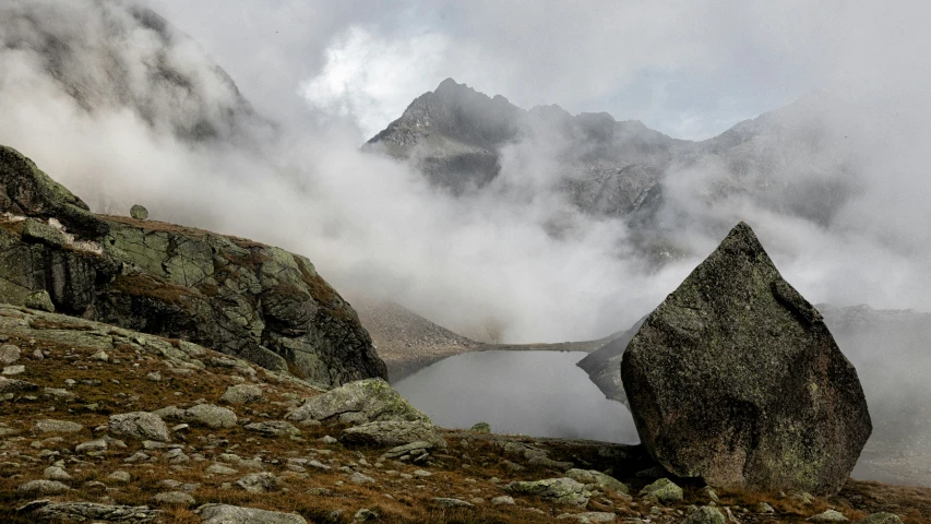 some rocks water clouds and a mountain