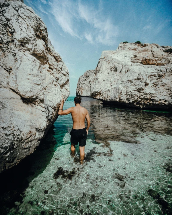 a person walking into water from the rocks