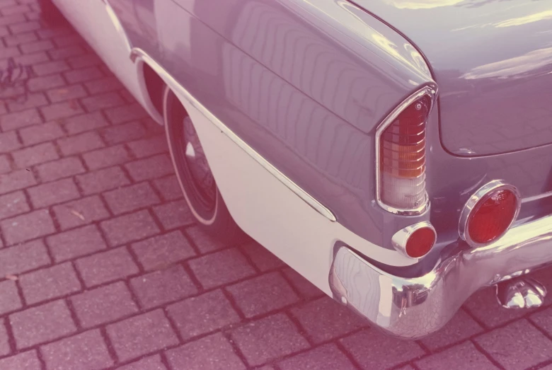 an old car is on the street with a brick sidewalk