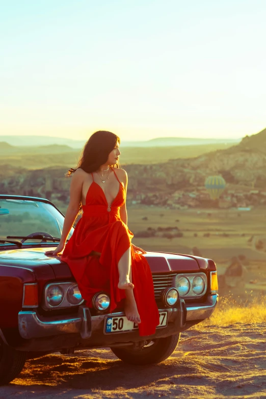 the woman is sitting on the hood of the truck