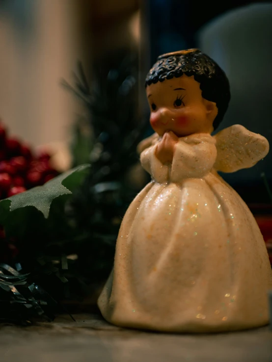 an angel statue next to a holly bush on a counter