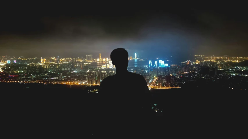 a man standing in the dark looking out at the city