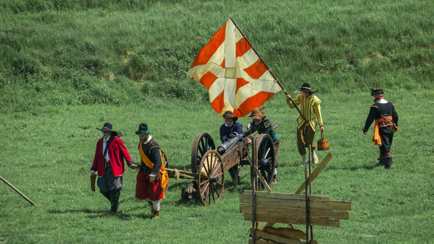 men in costumes walk behind a cart carrying a flag