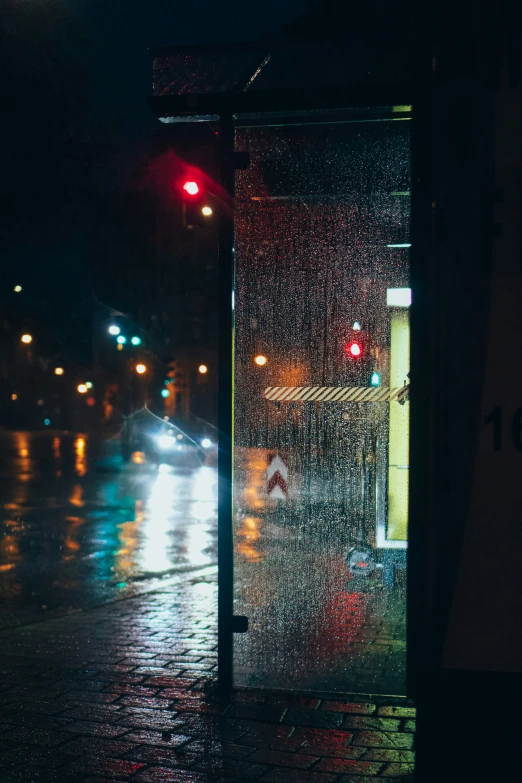 rain drops falling down the sidewalk outside a bus stop