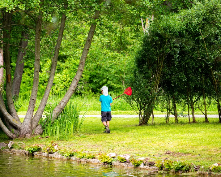 a boy is holding an object in his hand while standing next to trees