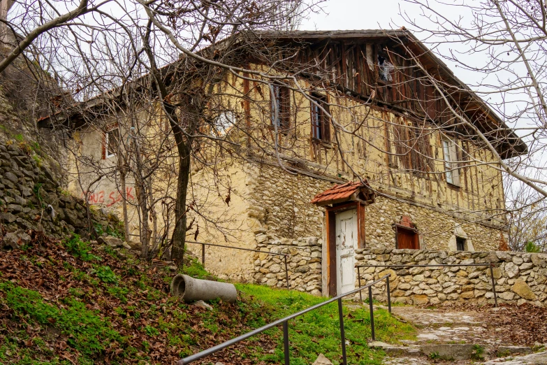 a small brown house next to a stone fence