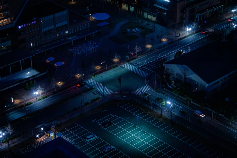 an overhead view of a city street at night with tennis courts lit up