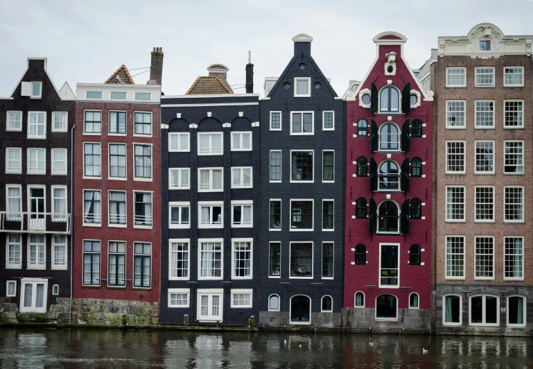 a row of different colored houses next to the water