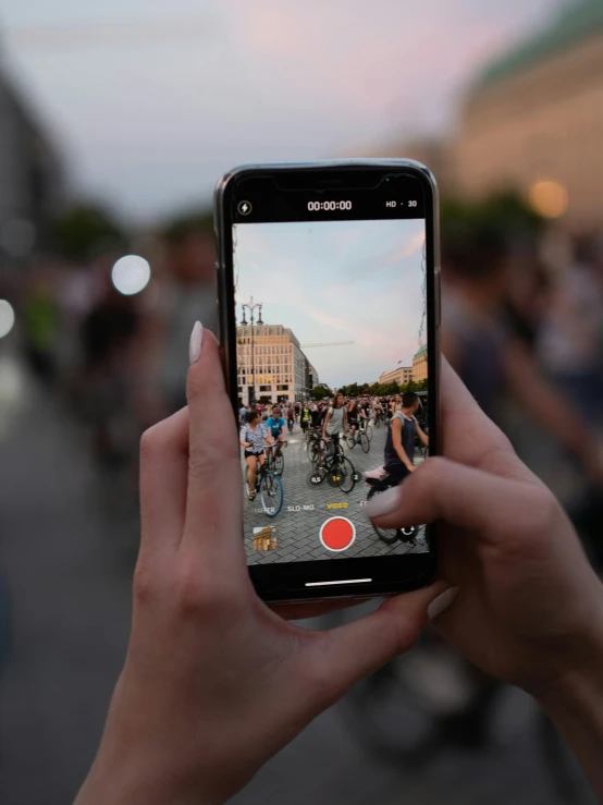 a person holding up a cell phone with people in the background