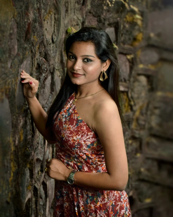 a woman posing in a dress near a rock wall