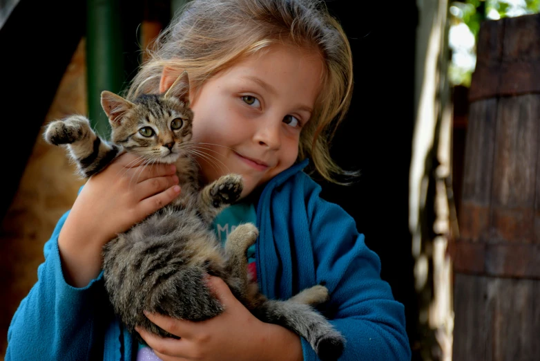 the little girl has her hands around a kitten