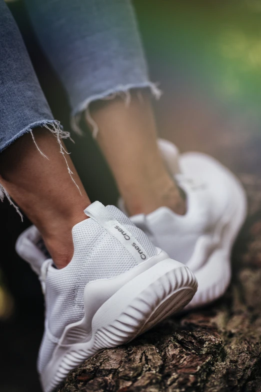 a person in white sneakers standing on top of some rocks