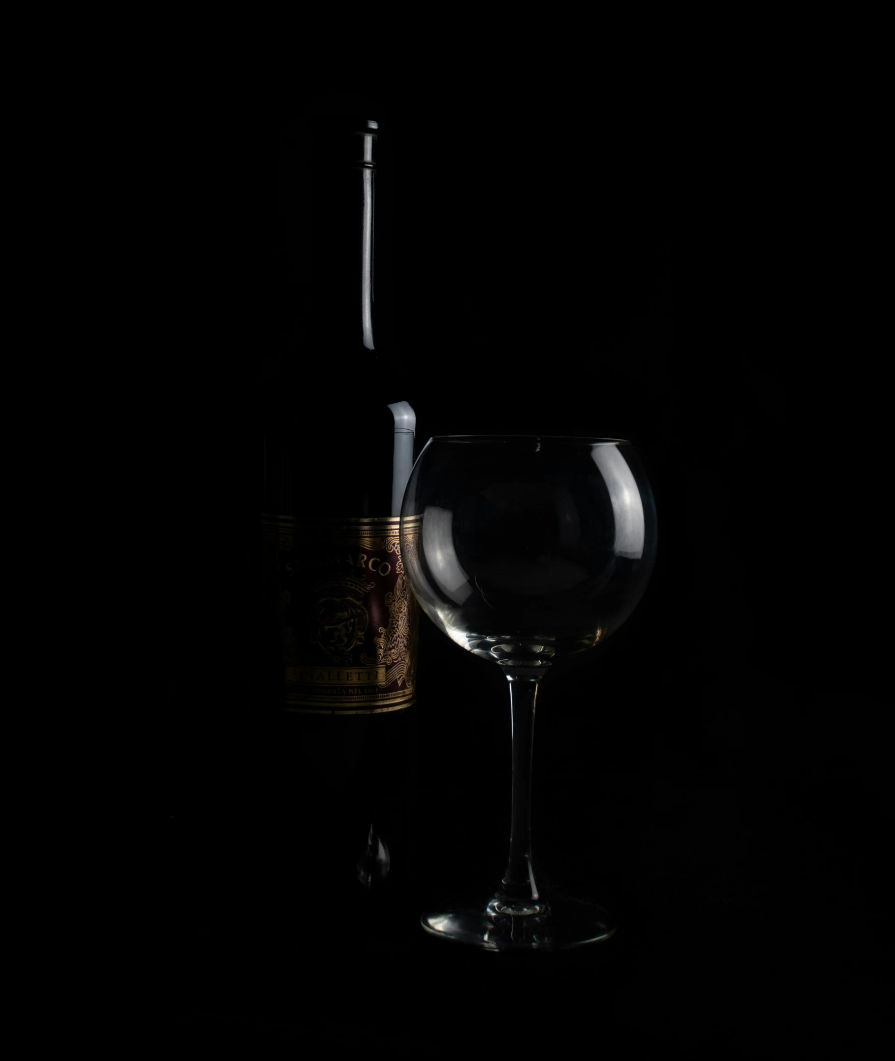 glass and wine bottle with dark background