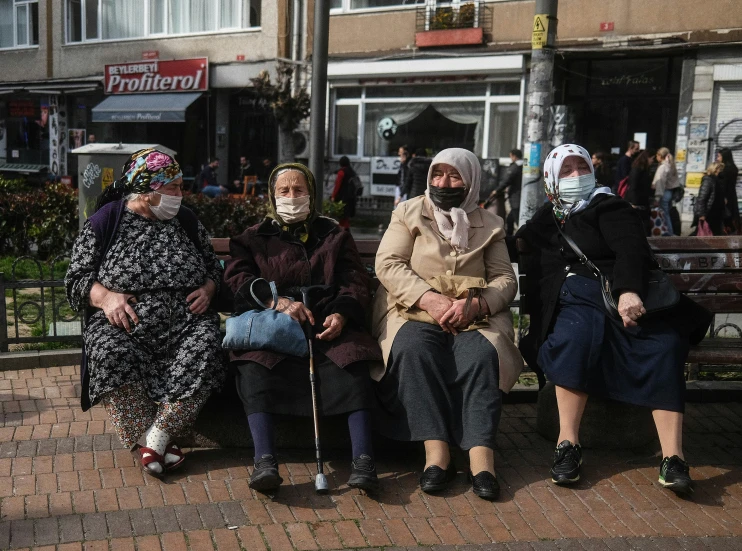 a group of four women sitting next to each other on a park bench