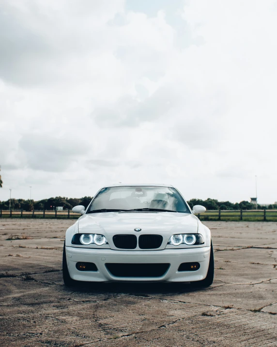 white bmw parked on a desert surface with clouds