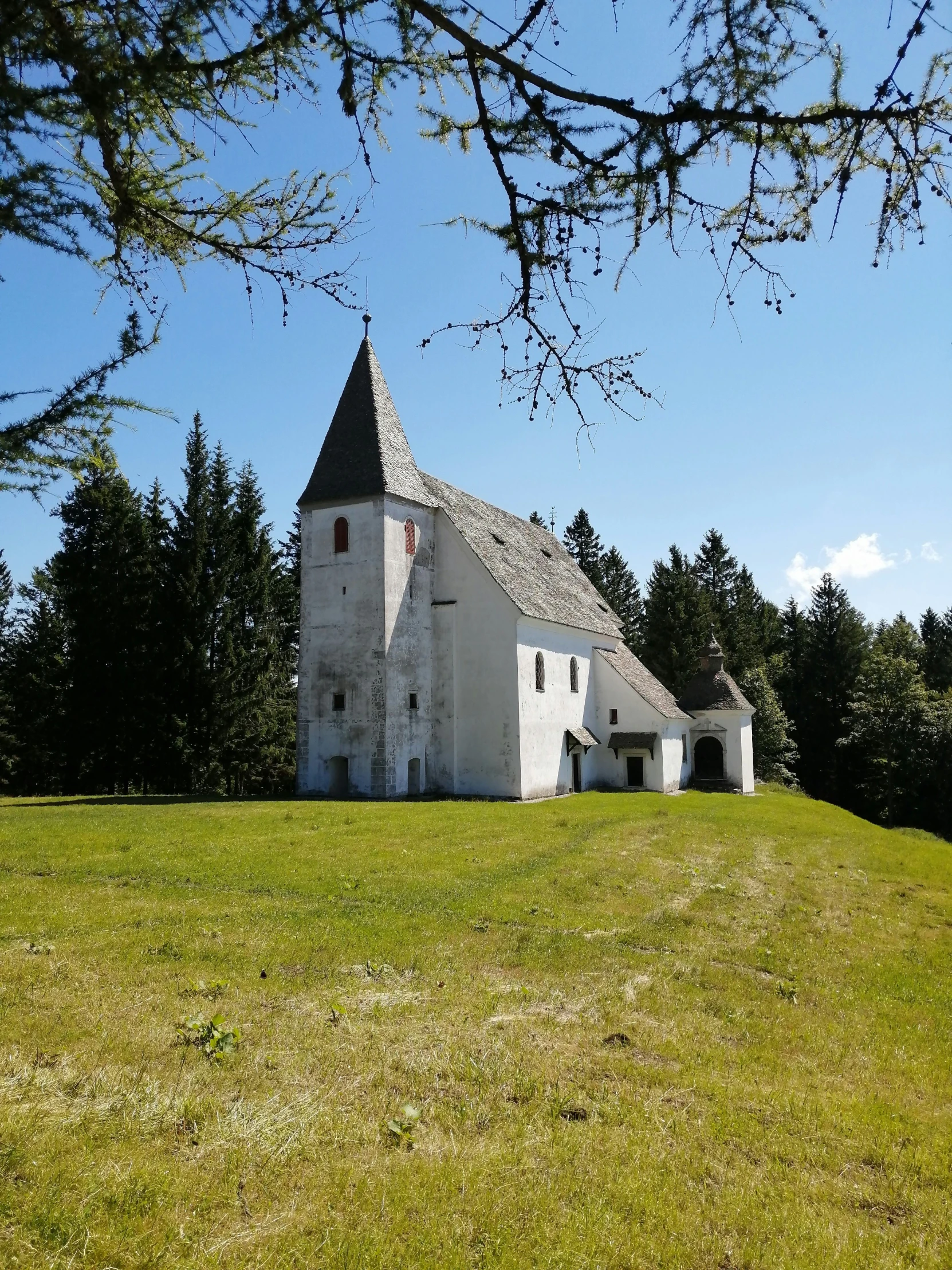 a large white church standing next to a lush green hillside