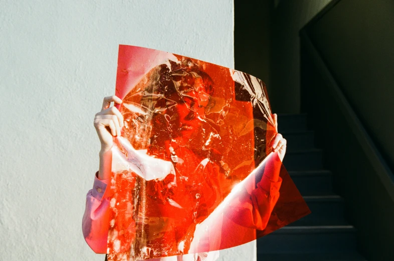 a person holding a piece of paper that has been torn into red