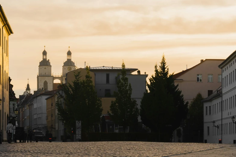 an empty street in the evening with buildings and a clock tower in the distance