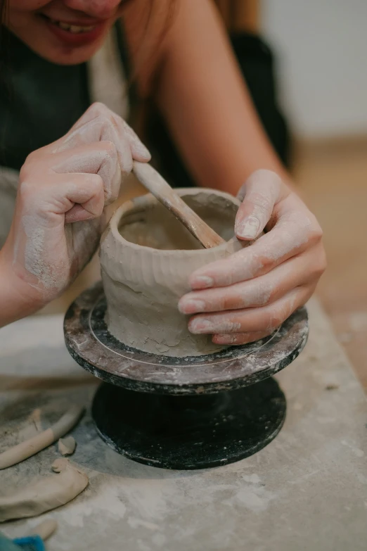 a woman is making clay pottery in a studio