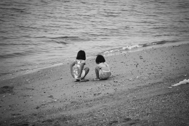 two women who are sitting on the sand