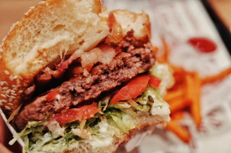 a sandwich with meat and vegetables is being held by a napkin