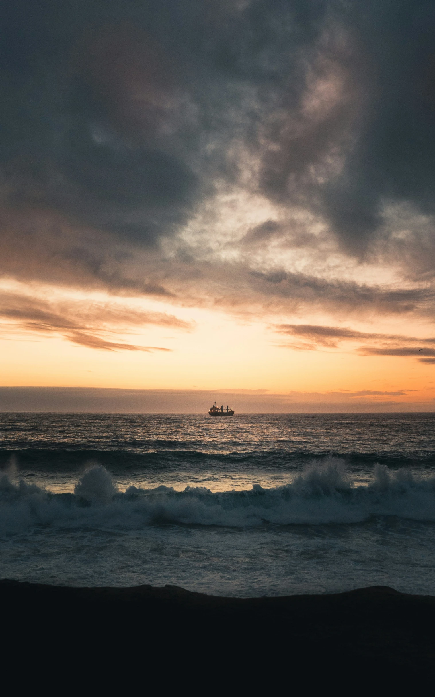 a boat sailing in the distance on the water at sunset