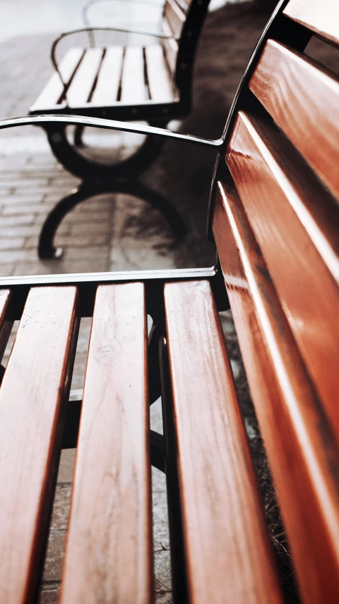 wooden bench with two benches behind it sitting on the sidewalk