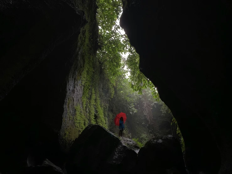 the person in the distance walks through an overhanging, dark cavern