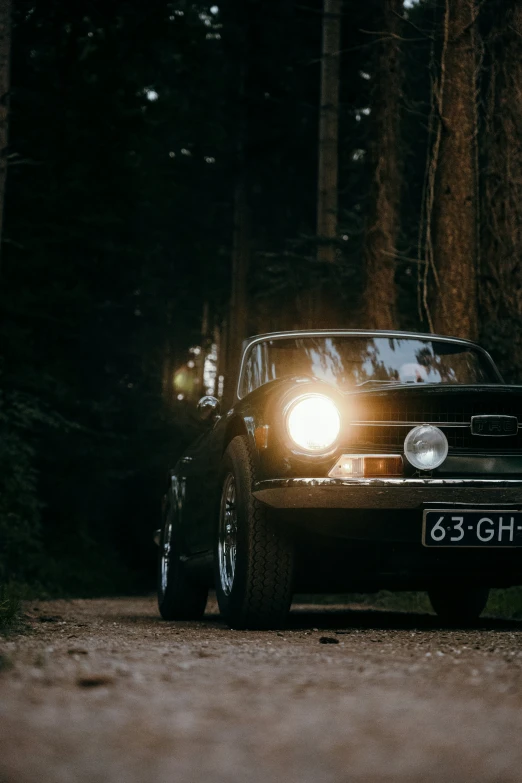 a black car driving down the road with its lights on