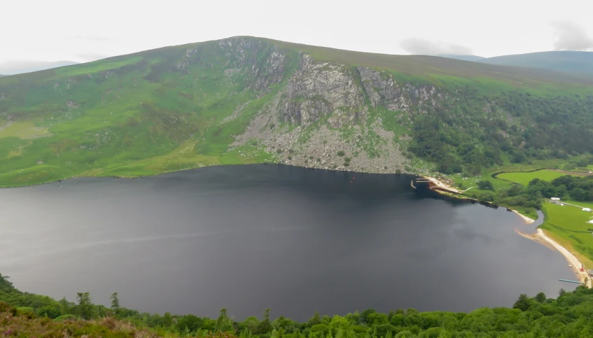 a mountain lake surrounded by mountains with lots of green grass