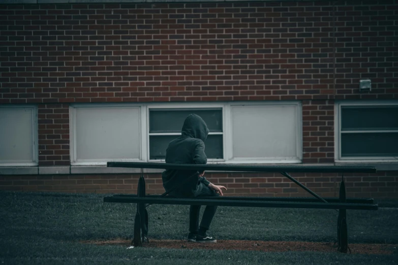 a man sits at a bench near a building