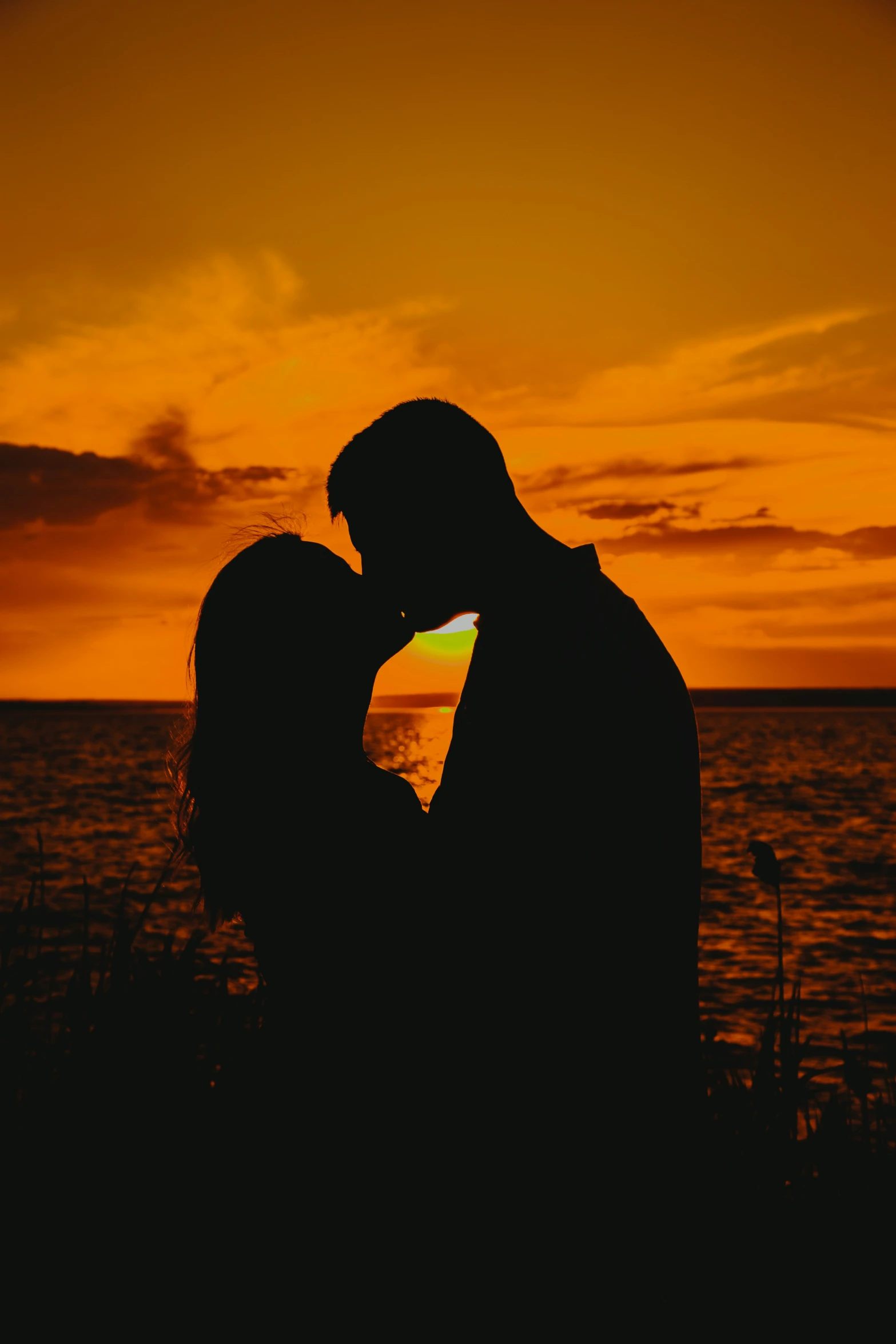 a couple standing close together at sunset by the ocean