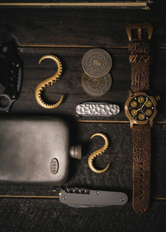 a leather case sitting next to a knife and an open watch