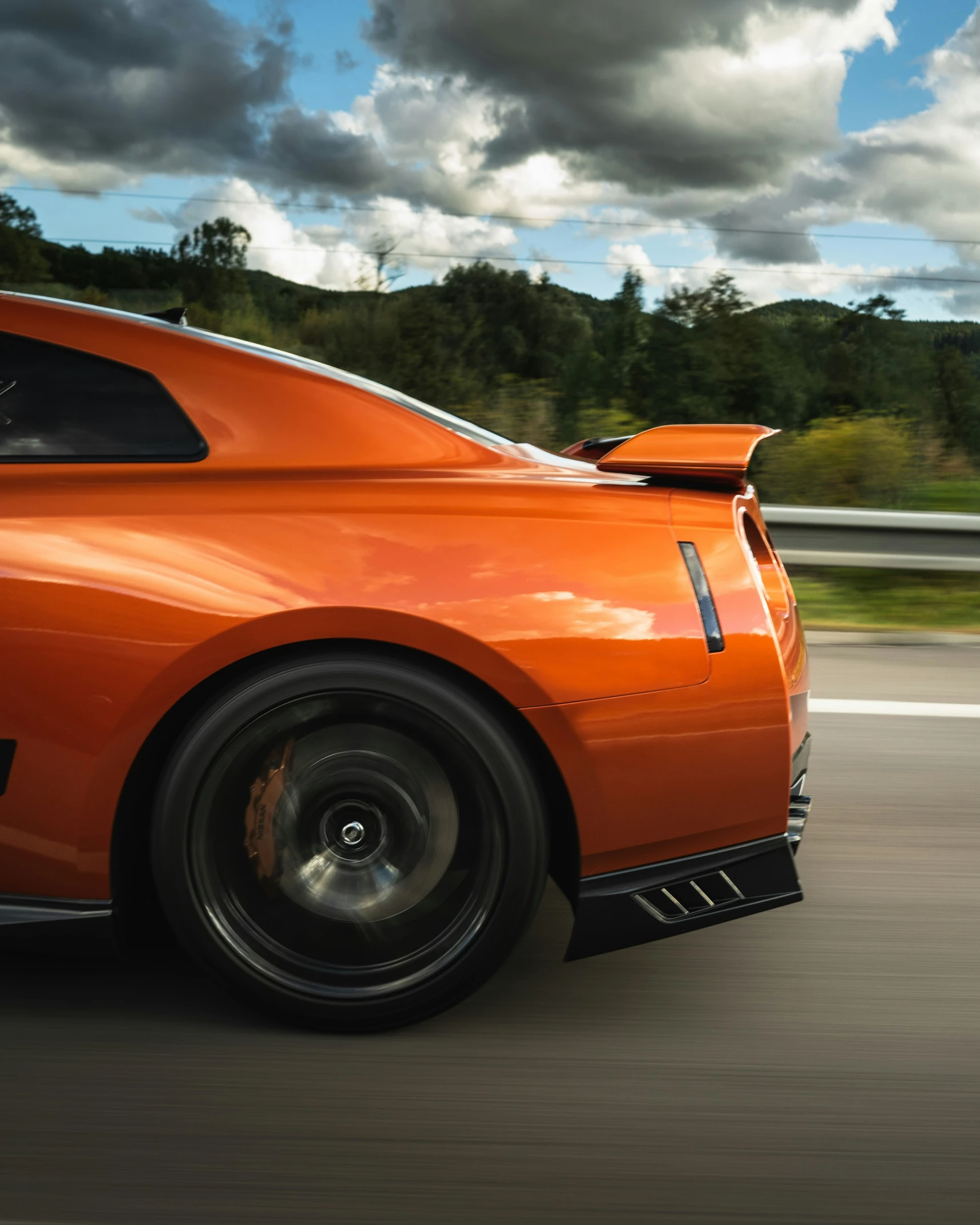 a very bright orange car driving down the highway