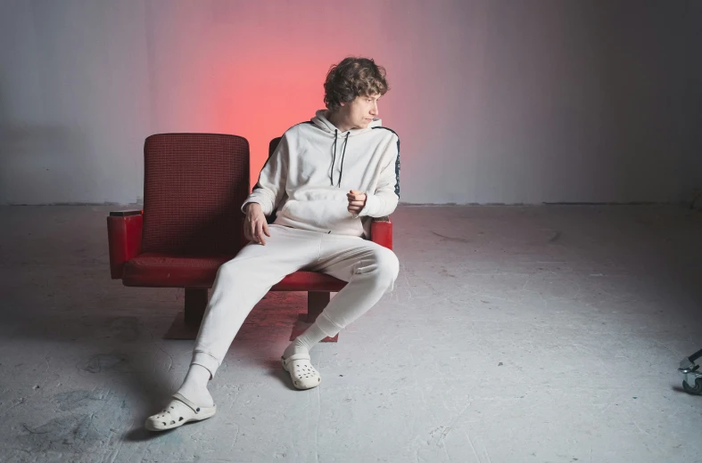 a person sitting on a red chair in front of a white wall