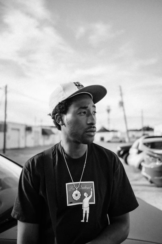 a man in a cap sits next to his parked car