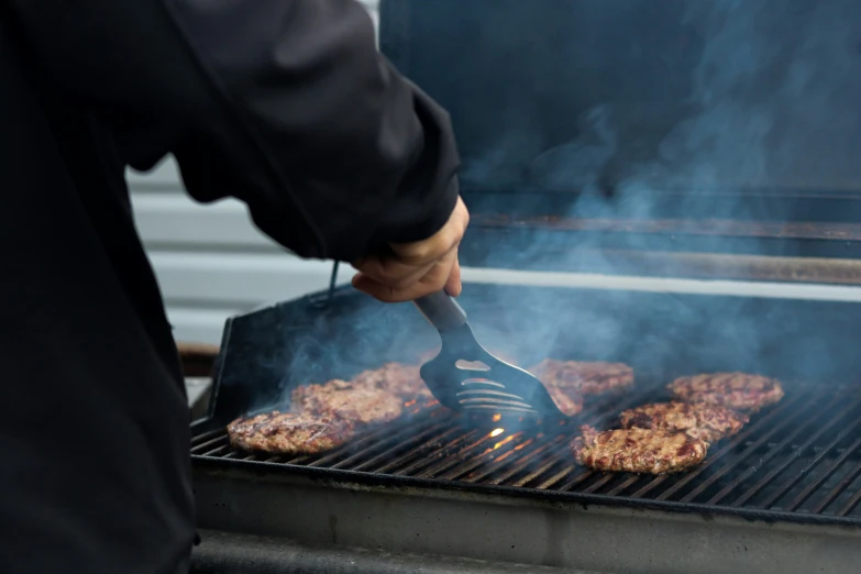 someone is cooking burgers on a grill