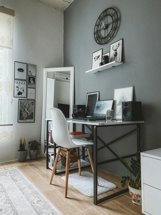 this gray and white bedroom has large windows, wood flooring and a small desk with a computer