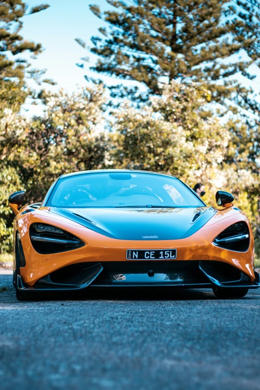 an orange sports car parked in front of trees