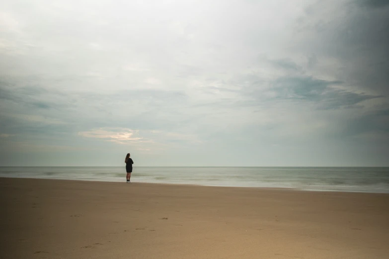 man standing on beach with arms out in the distance