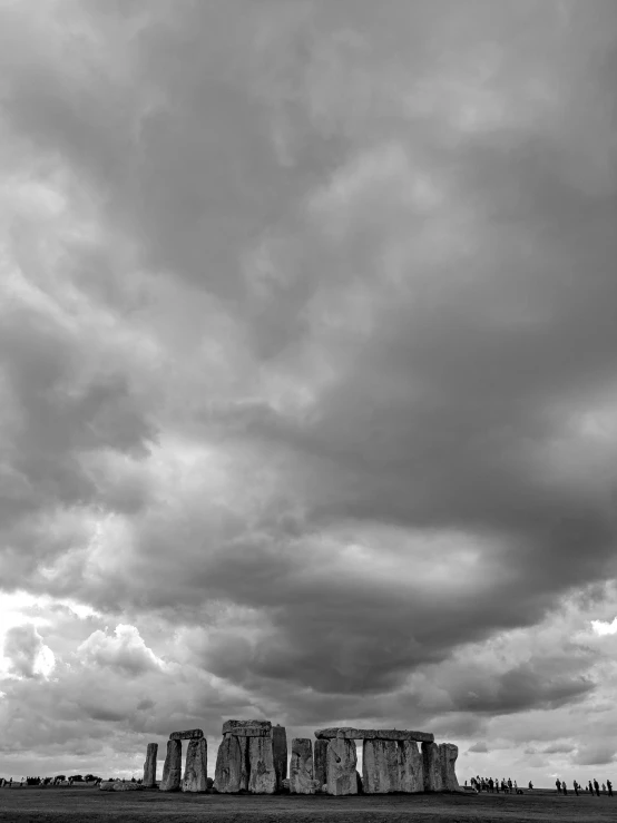 a black and white po of stonehenges under a dark cloud