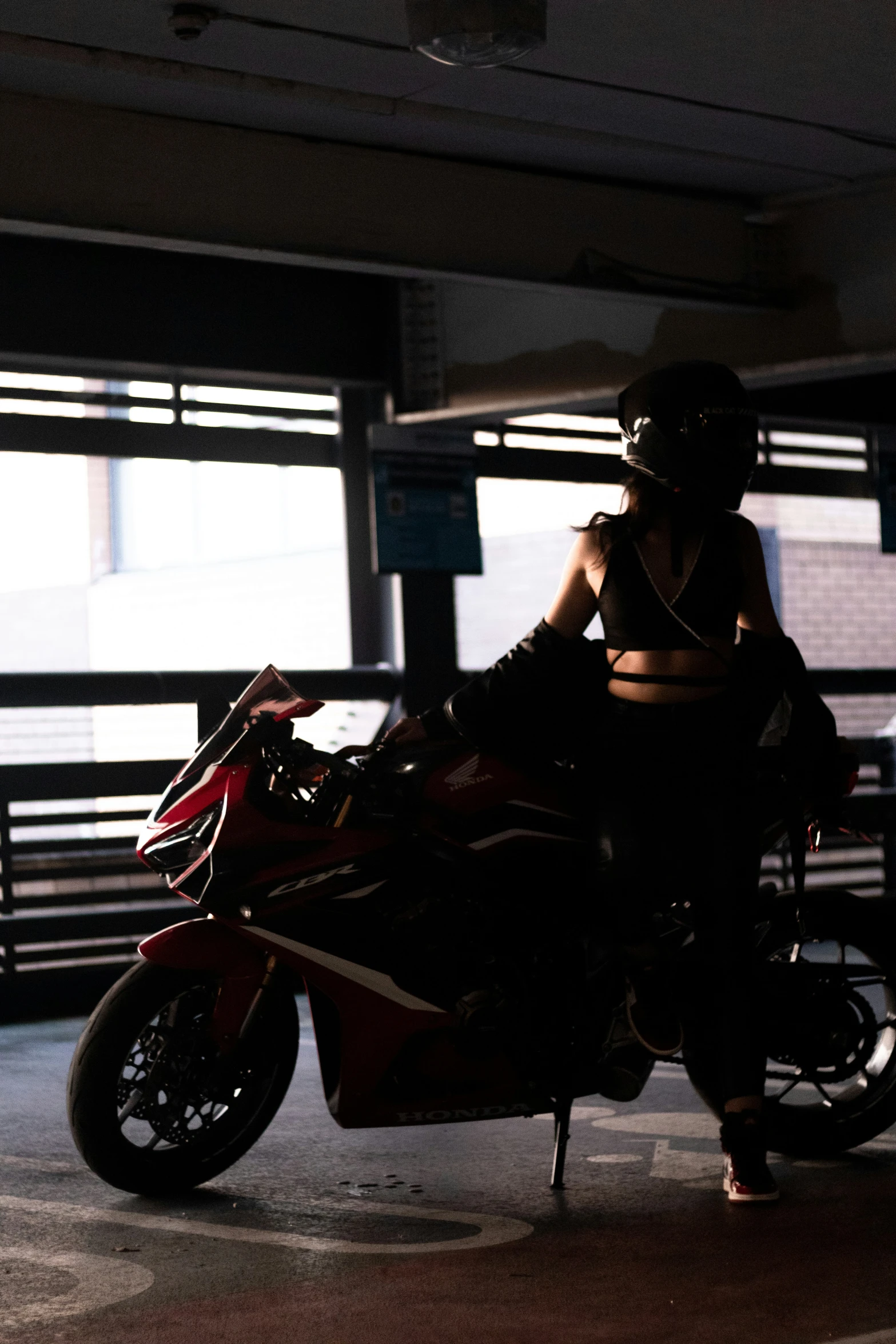 a person sitting on a motorcycle in a large parking garage