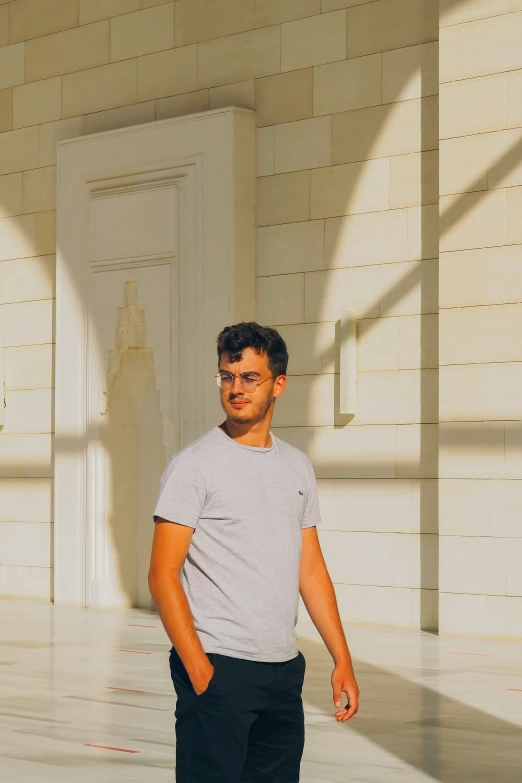 a man in glasses standing in the middle of an empty hallway