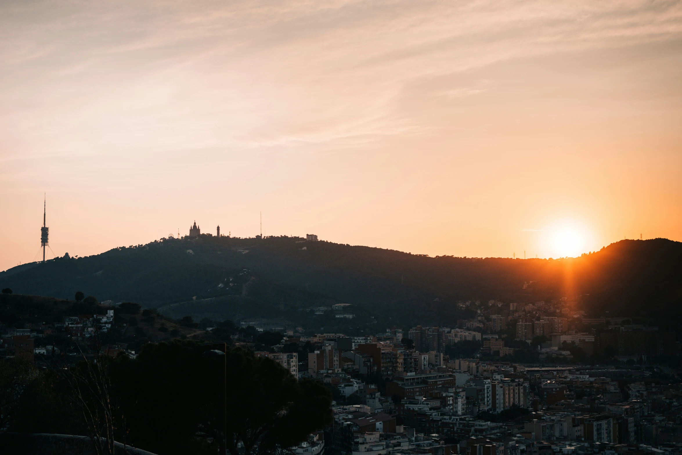 the sun is shining over the hills behind a town