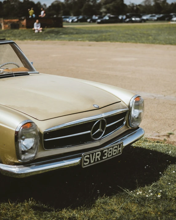 an old mercedes car is parked near a field